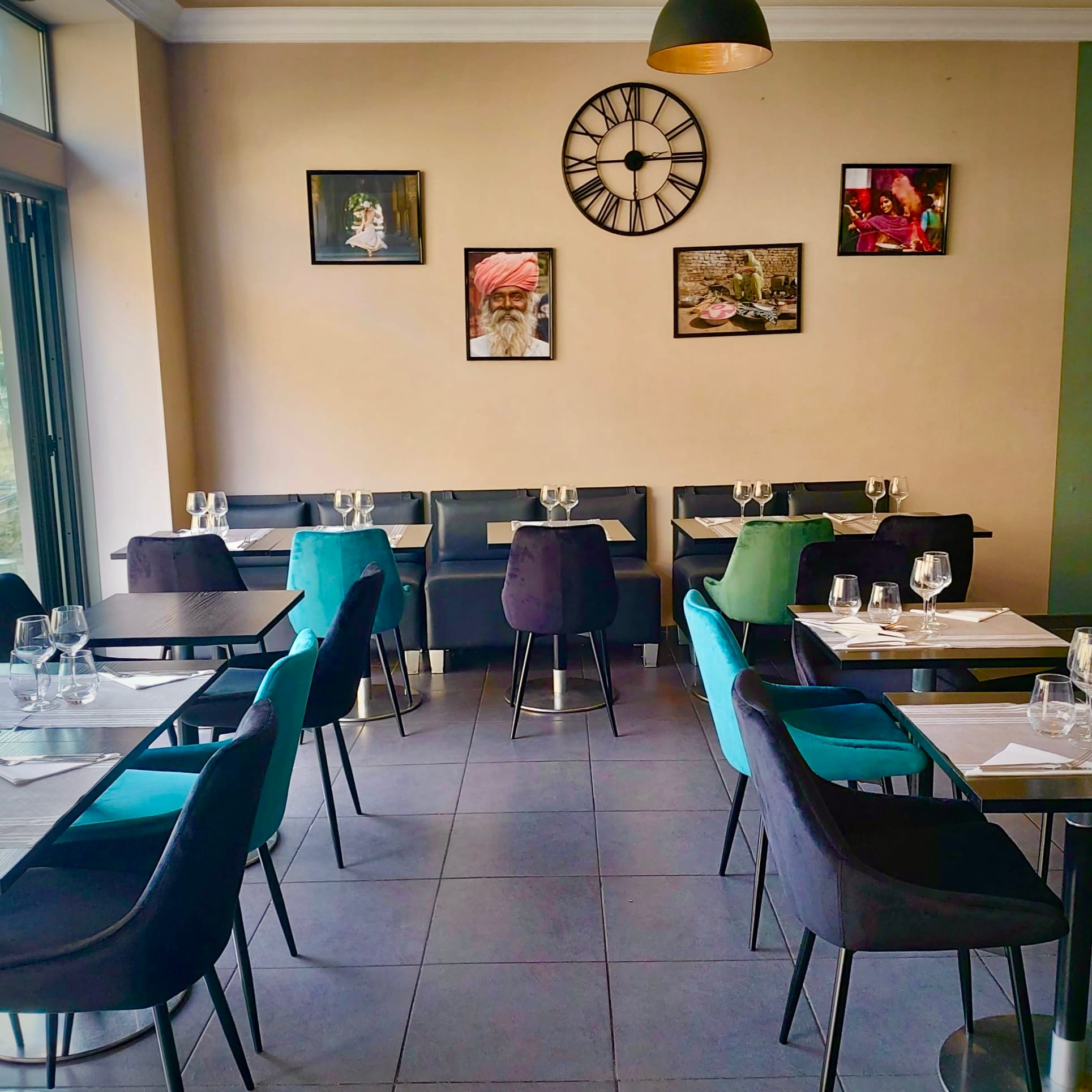 Gallery wall of Rajasthani portraits above colorful velvet dining chairs