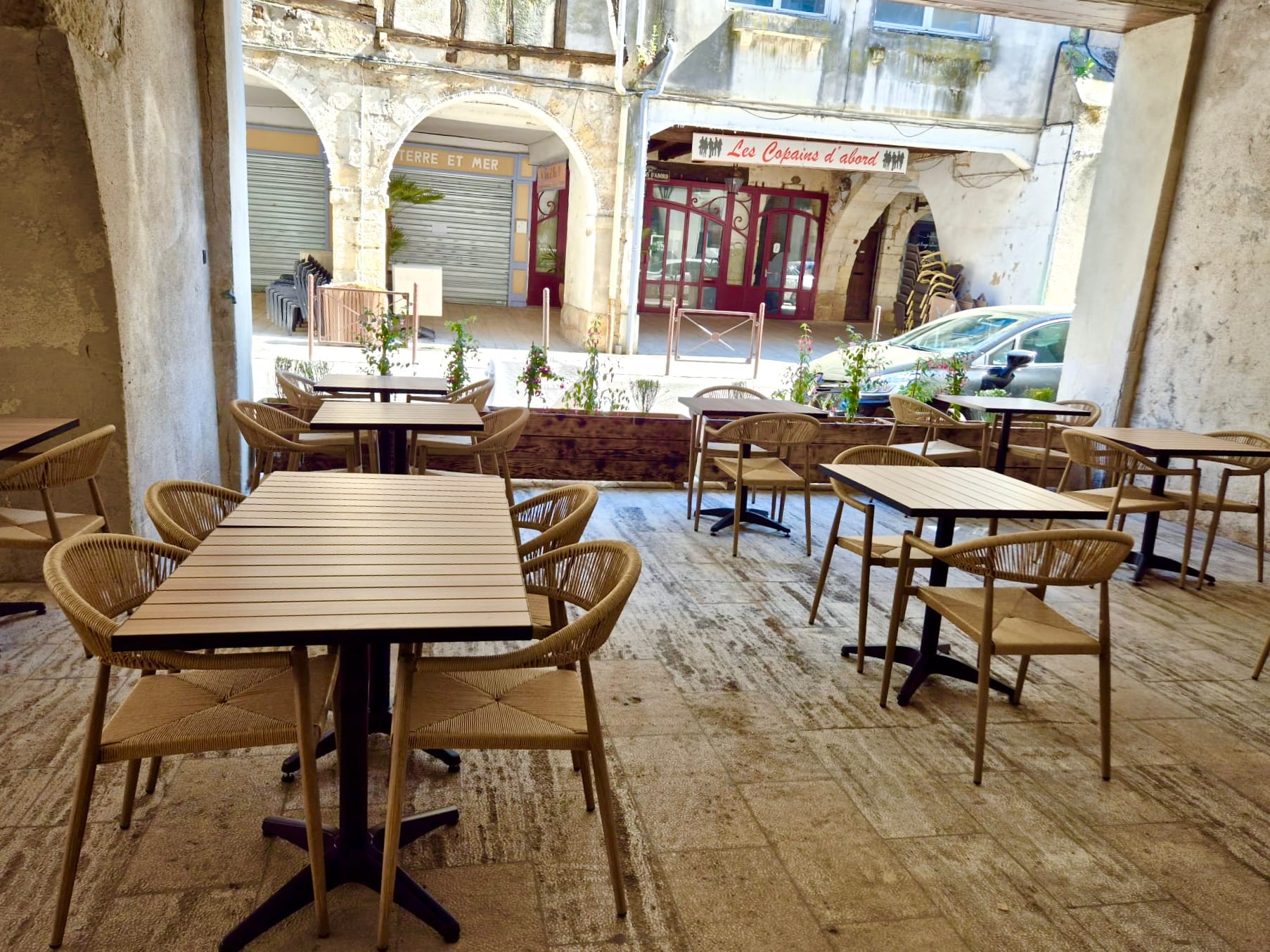 Covered terrace with woven chairs overlooking the historic town square