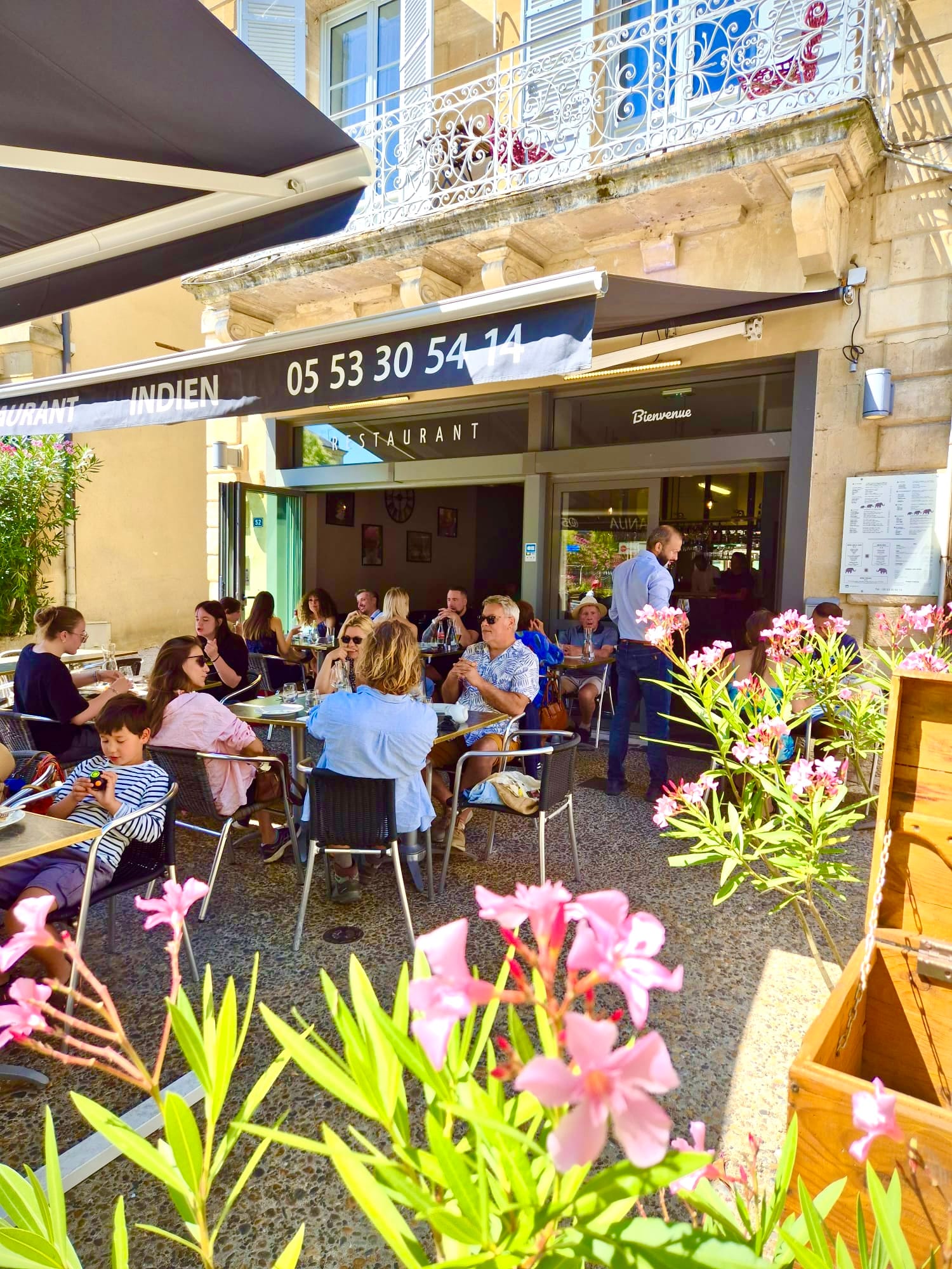 Bustling outdoor terrace filled with guests under the restaurant awning