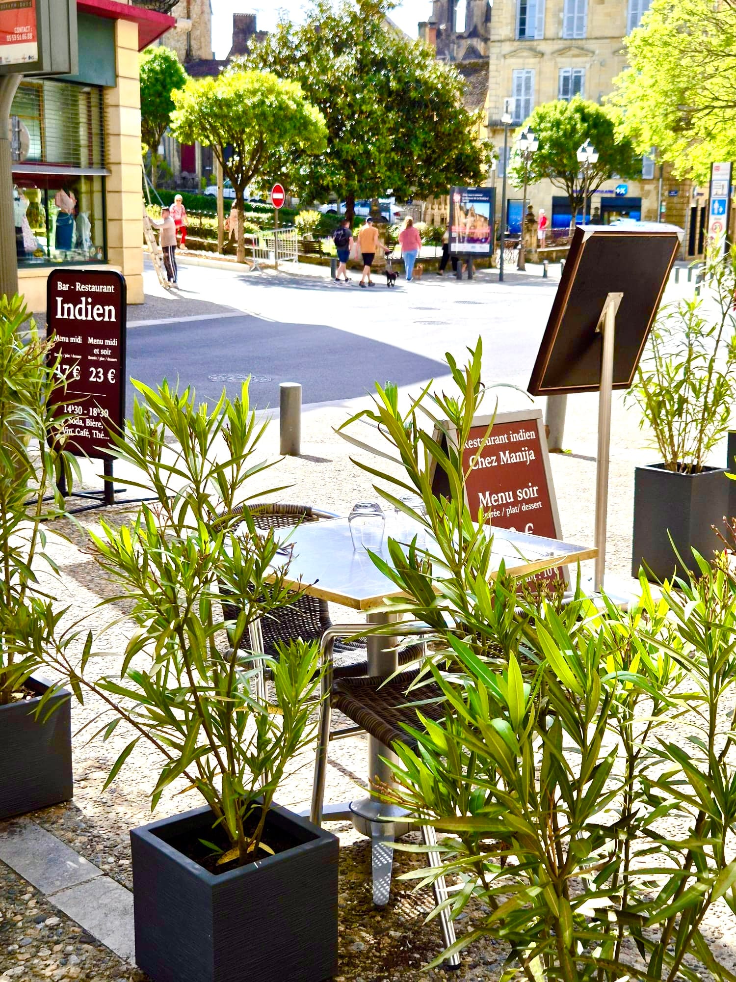 Sidewalk signs for Chez Manija on the sunny town square
