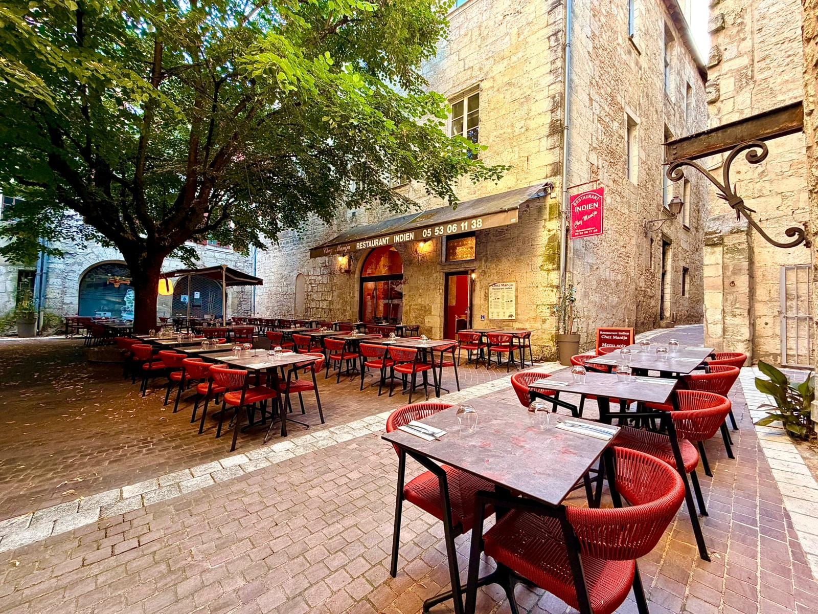 Charming stone courtyard terrace with red chairs and a historic facade