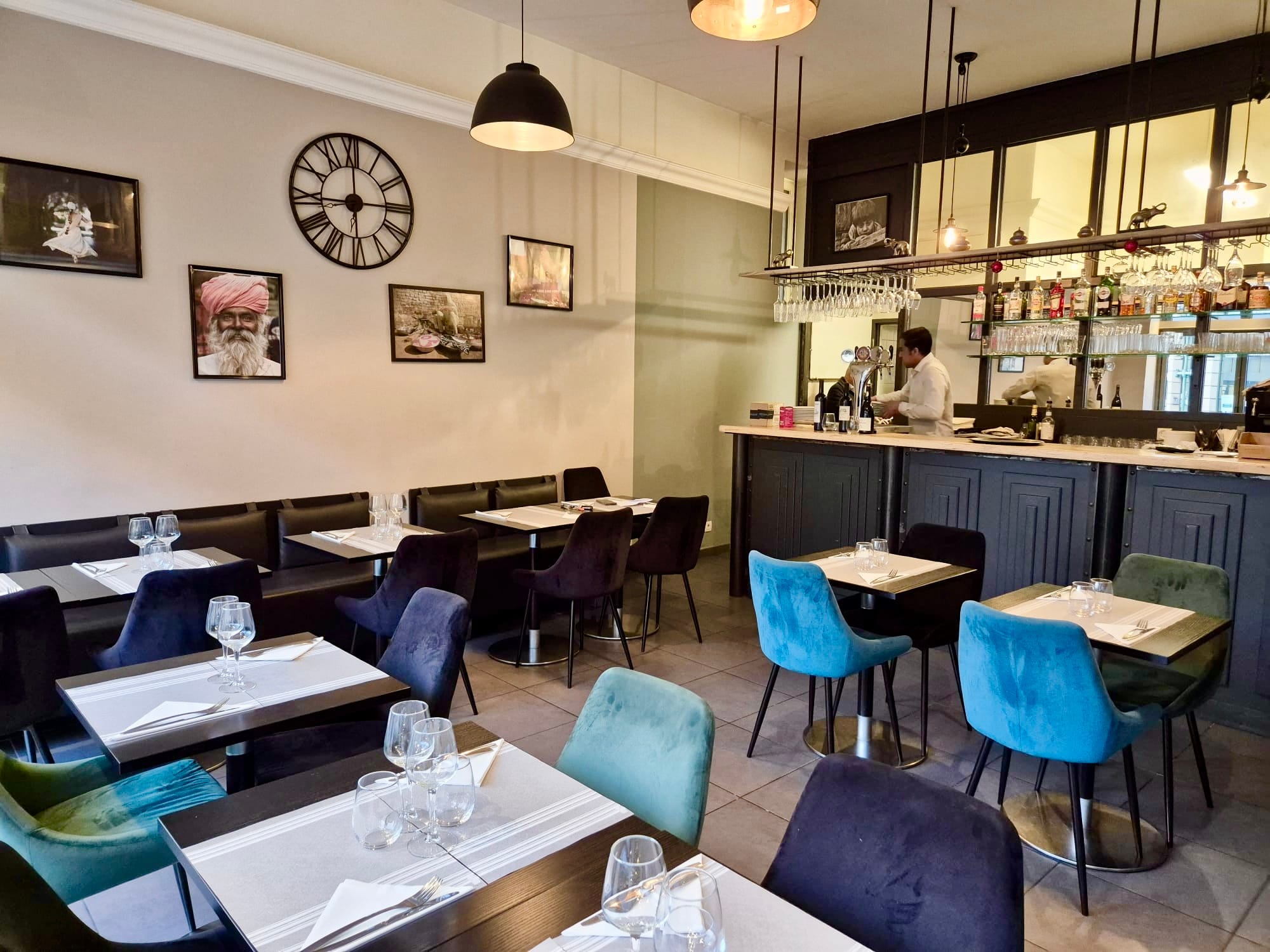 Indoor bar and dining area with Indian portraits and jewel-toned chairs